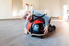 Kleiner Junge lehnt sich über ein Fahrgerät, welches aussieht wie ein Marienkäfer